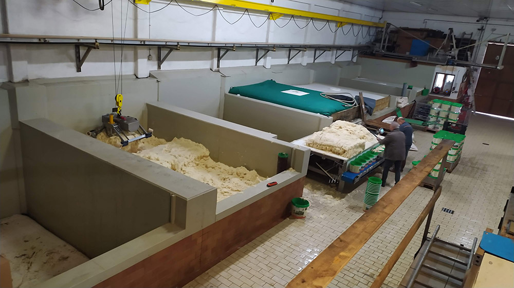 シュークルートリーのそれぞれの発酵槽からクレーンでシュークルートを手前の作業台に移動させ、手作業で容器に詰めて製品にしていきます。それぞれの発酵槽は50トンのキャベツが入ります。